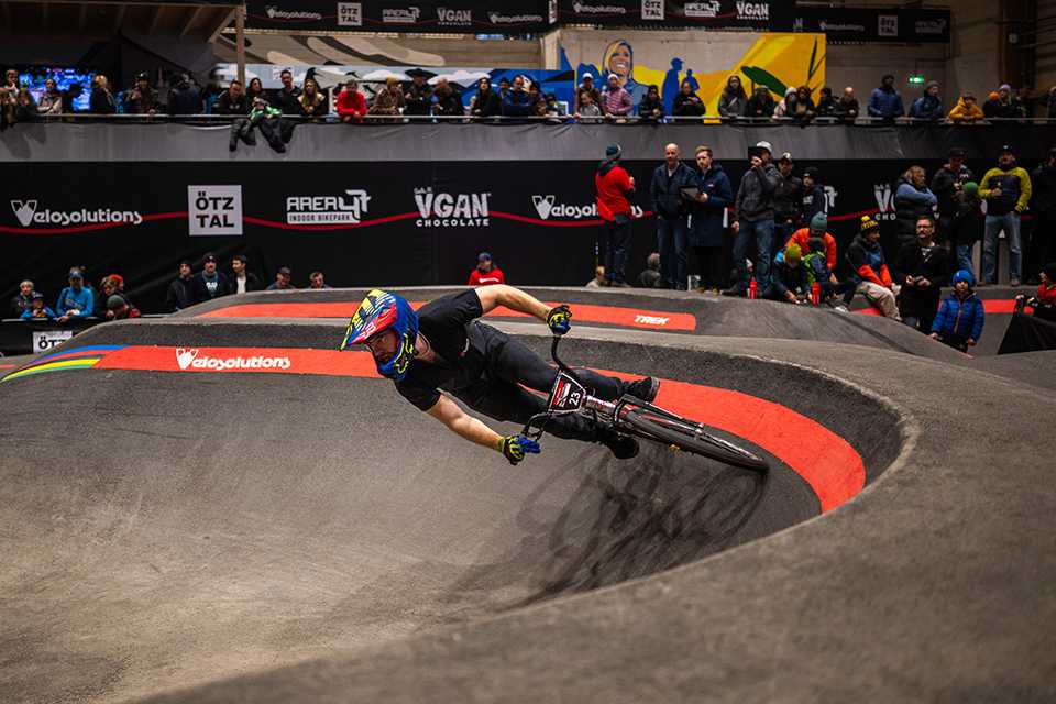 UCI Pump Track WM: Radfahrer auf der Strecke in AREA47. Zuschauer im Hintergrund.