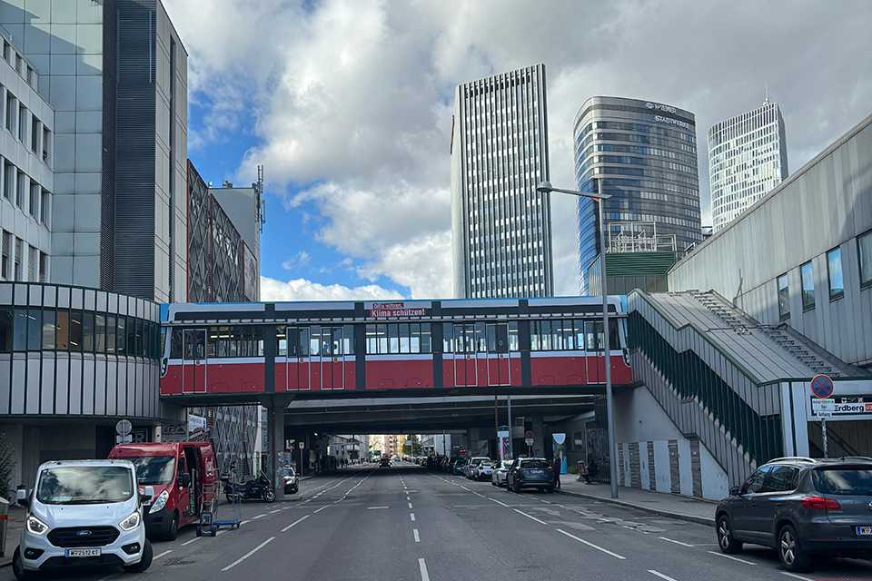 Wiener Linien Steg Erdberg, Wien. Roter Steg mit Branding vor Wolkenkratzern. Verkehr und Architektur in Wien.