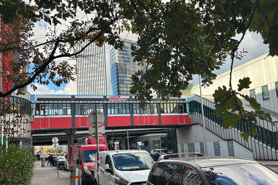 Wiener Linien Steg Erdberg: Rote Straßenbahn auf Brücke, Wien Skyline.