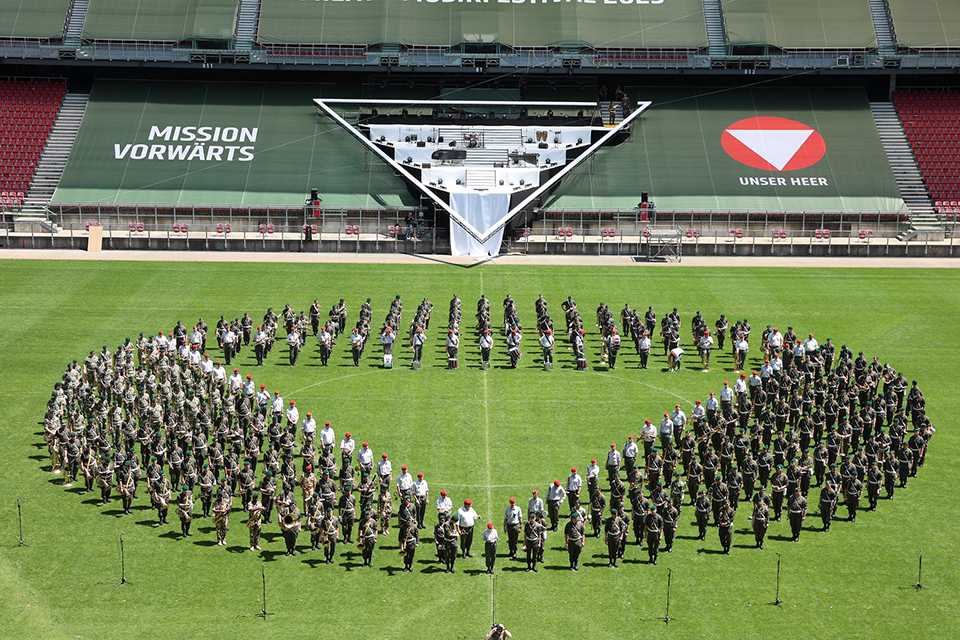 Militärmusik Festival 2023 Klagenfurt: Orchesterformation auf Rasen vor Bühne.