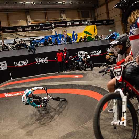 UCI Pump Track WM: BMX-Fahrer auf der Strecke in AREA47. Zuschauer beobachten den Wettbewerb.